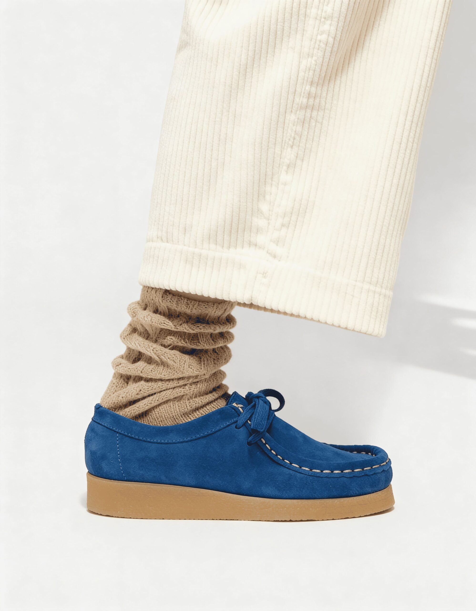 Chaussure en daim bleu portée avec un pantalon en velours écru et des chaussettes beiges.