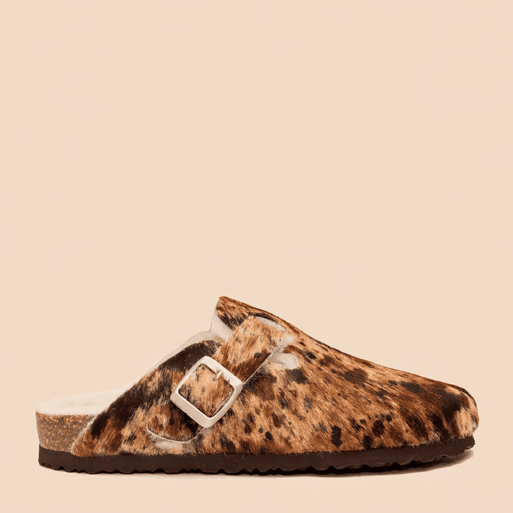 Zueco de pelo con estampado animal print y hebilla lateral, fotografiado de perfil sobre fondo neutro.